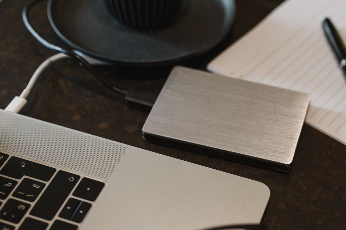 Portable storage drive connected to a laptop on a desk.